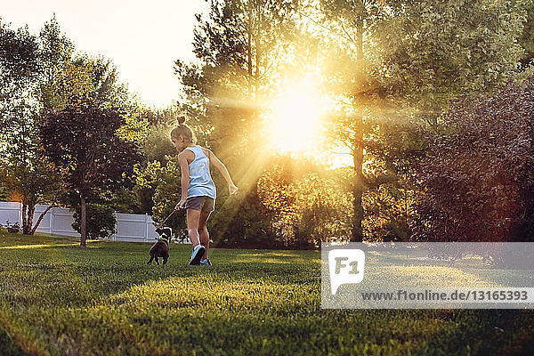 Rückansicht eines Mädchens im Park beim Laufen mit einem Boston-Terrier-Welpen