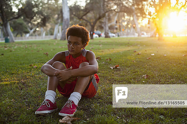 Traurig aussehender Junge sitzt im Park