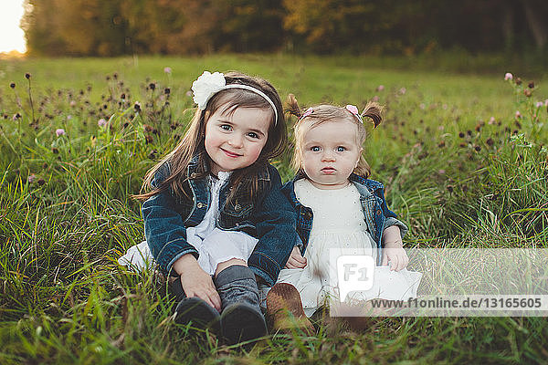 Porträt eines jungen Mädchens und einer kleinen Schwester im Feld