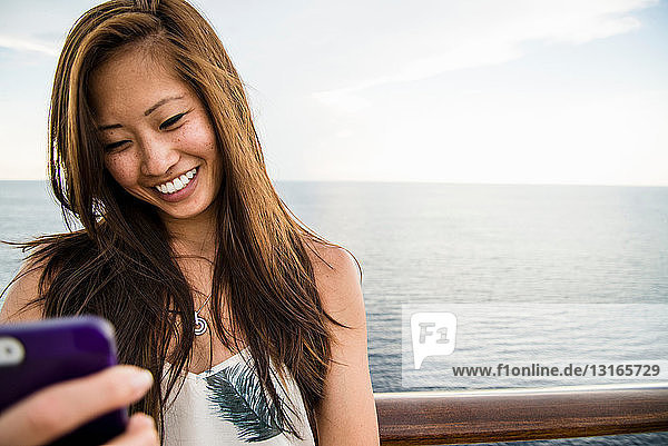 Junge Frau benutzt Mobiltelefon auf See