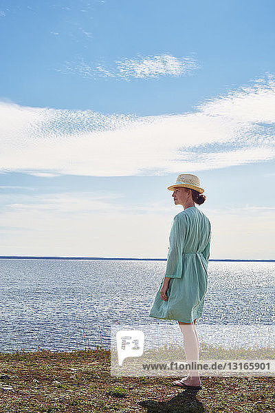 Mittelgroße erwachsene Frau im grünen Kleid am Meer stehend  Eggegrund  Schweden