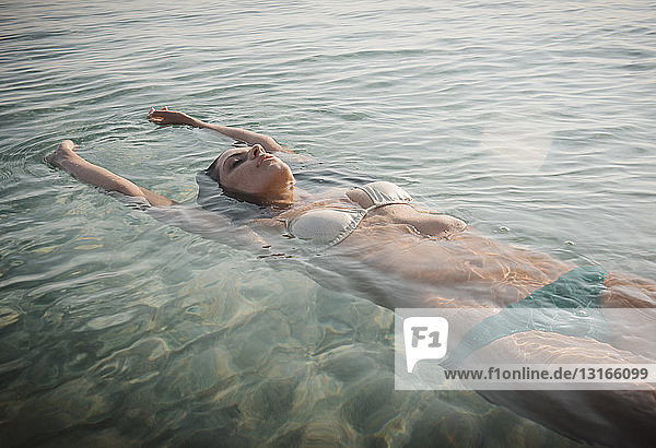 Junge Frau im Bikini schwebt im Meer