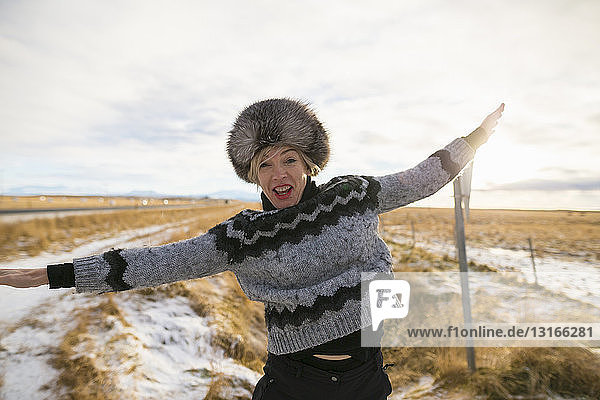 Reife Frau posiert mit offenen Armen auf schneebedecktem Feld  Island