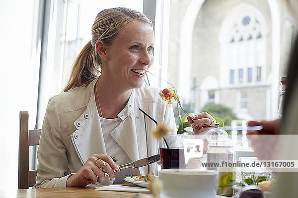 Mid adult woman having lunch with friend in cafe