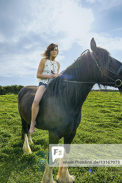 Porträt einer jungen Frau auf einem Pferd im Feld