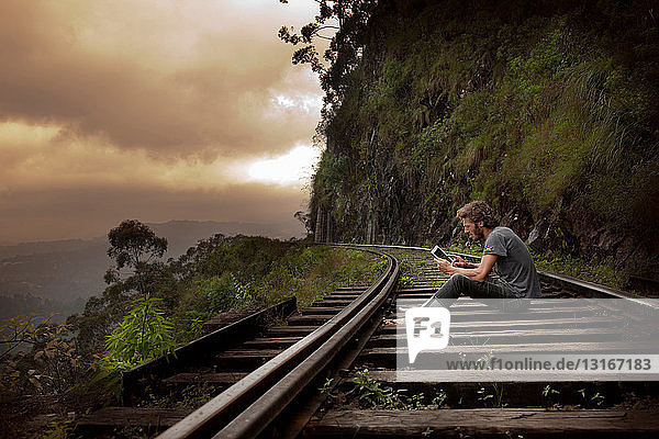 Man using tablet computer on tracks