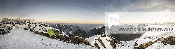 Panorama eines jungen männlichen Bergwanderers der mit einem Smartphone in den bayerischen Alpen fotografiert Oberstdorf Bayern Deutschland