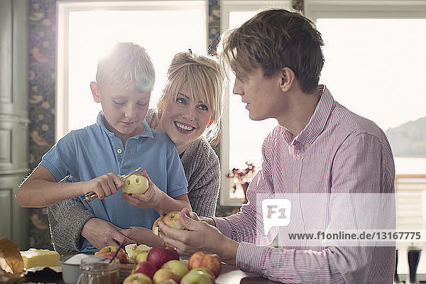 Eltern und Sohn schälen Bio-Äpfel in der Küche