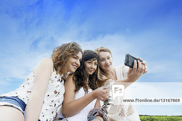 Drei junge Frauen im Feld posieren für Selfie auf Smartphone