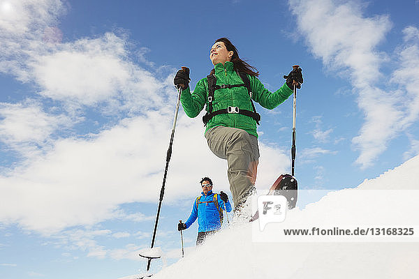 Niedrigwinkelaufnahme eines mittleren erwachsenen Paares beim Schneeschuhwandern in den Dolomiten  Eisacktal  Südtirol  Italien