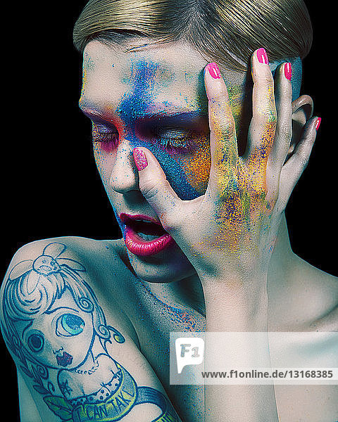 Young woman  naked  touching face  colourful powder and paint on face