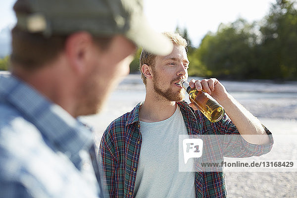 Young man taking a drink from a beer bottle  looking away