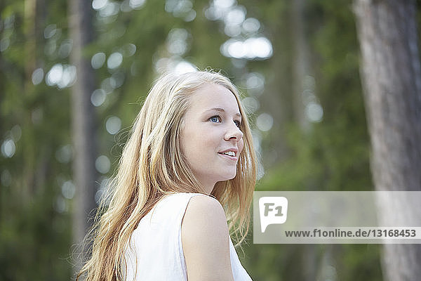Porträt einer Teenagerin mit langen blonden Haaren beim Wegschauen