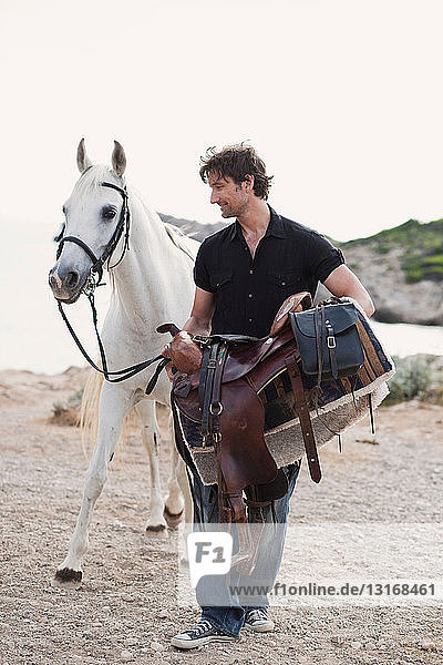 man carrying horses saddle