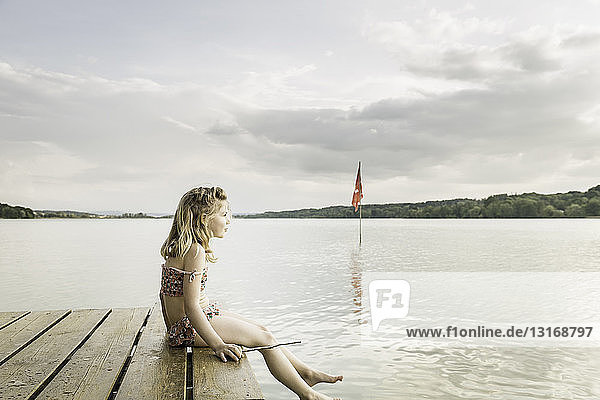 Bikinitragendes Mädchen am Seepier sitzend, München, Bayern, Deutschland