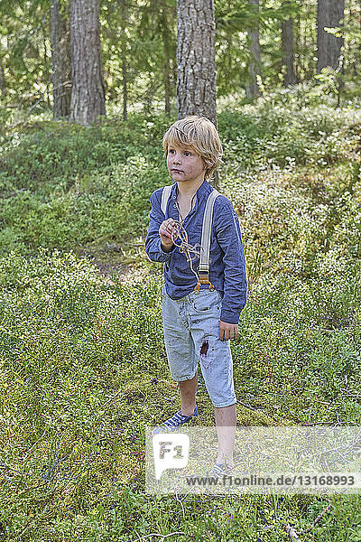 Portrait of young boy wearing retro clothes standing in forest