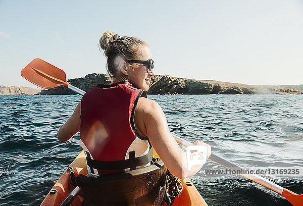 Rückansicht einer mittleren erwachsenen Frau beim Seekajakfahren  Menorca  Balearen  Spanien