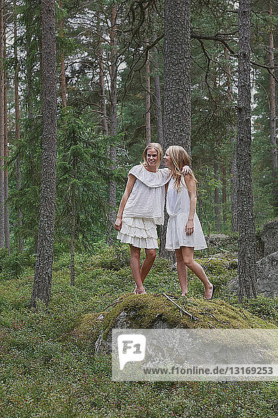 Mädchen im Teenageralter stehen auf Felsen im Wald