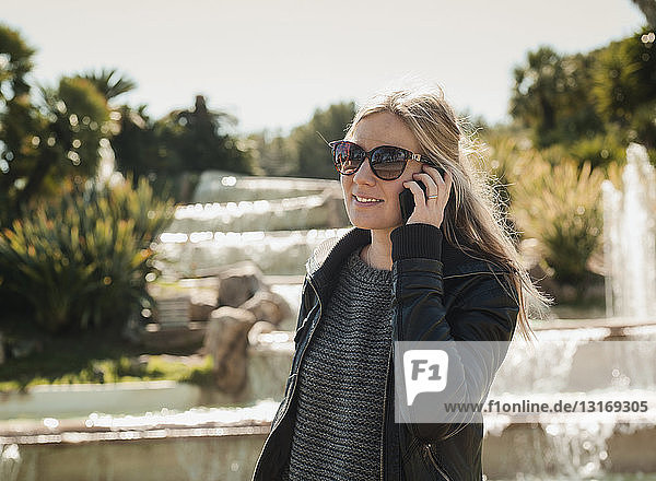 Touristin im Gespräch mit einem Smartphone vor dem Brunnen auf dem Montjuic-Hügel  Barcelona  Spanien