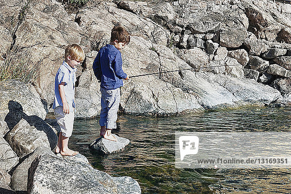 Zwei Jungen stehen auf Felsen und angeln  Utvalnas  Schweden