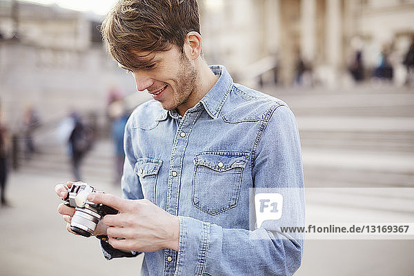 Mid adult man reviewing camera photographs  Trafalgar Square fountain  London  UK