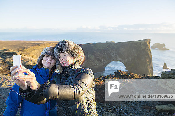 Mother and daughter taking self portrait  Dyrholaey Nature Reserve  Dyrholaey  a peninsula on the south coast of Iceland