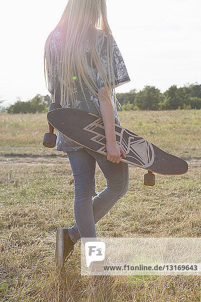 Junge Frau mit Skateboard in der Hand