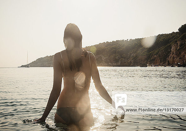 Rückansicht einer jungen Frau im Bikini  die im Meer watend  Menorca  Balearen  Spanien
