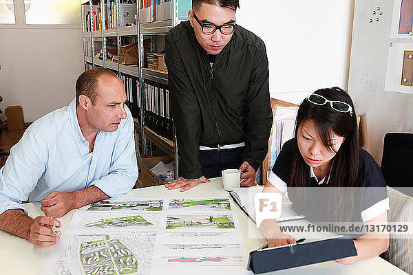 Team of three architects inspecting ideas for blueprint in office