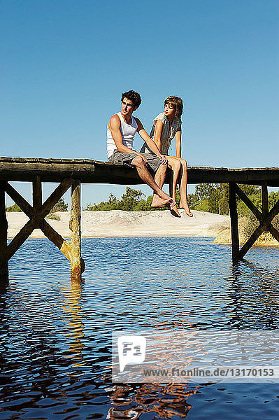 Teenage couple sitting on jetty