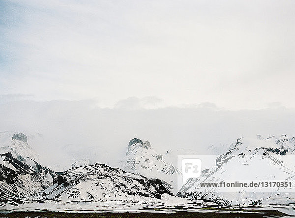 Blick auf schneebedeckte Berge und niedrige Wolken  Island