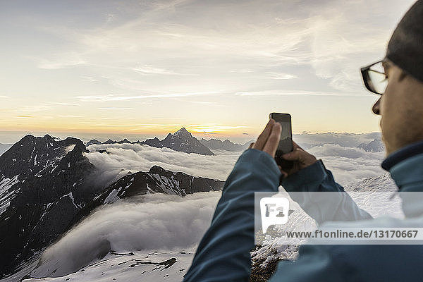 Young man photographing sunrise on smartphone  Bavarian Alps  Oberstdorf  Bavaria  Germany