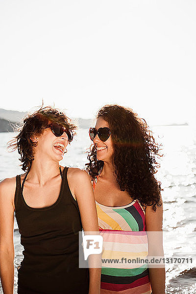 Lachende Frauen mit Sonnenbrille am Strand