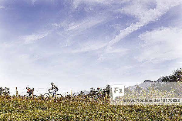 Side view of family riding bicycles on farmland