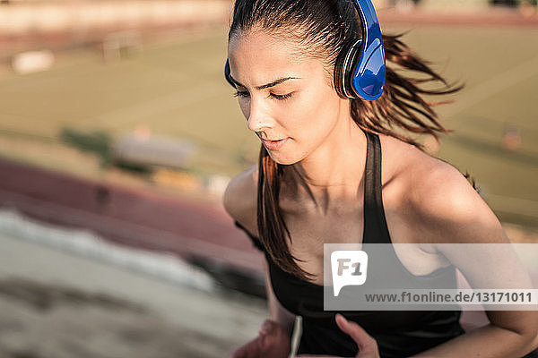 Junge Frau trägt Kopfhörer beim Laufen