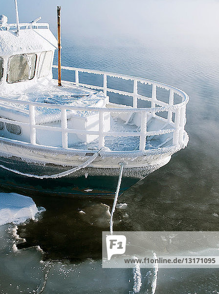 Ein Boot das in der extremen Kälte an einem See in Jarfjord bei Kirkeness Region Finnmark Nordnorwegen vor Anker liegt