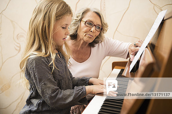 Großmutter unterrichtet Enkelin Klavier