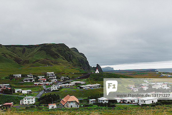 Hochwinkelansicht eines Küstendorfes an einem üppig grünen Berg  Vik  Island