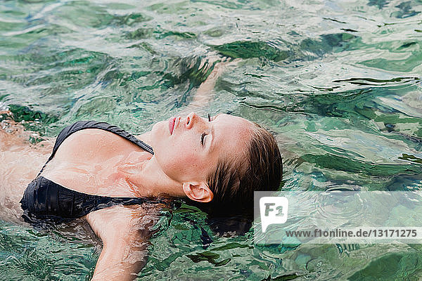 Frau schwimmt im Wasser mit geschlossenen Augen