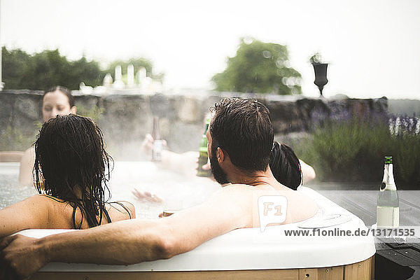 Male and female friends enjoying in hot tub during weekend getaway