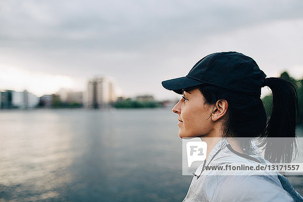 Side view of female athlete looking away while standing by sea against sky