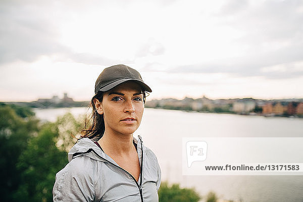 Porträt einer selbstbewussten Sportlerin  die auf einem Hügel am Meer gegen den Himmel steht