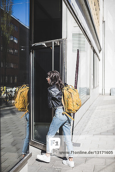 Geschäftsfrau mit Rucksack  der die Tür am Eingang des Büros öffnet