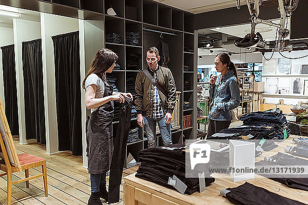 Saleswoman showing jeans to customers at store