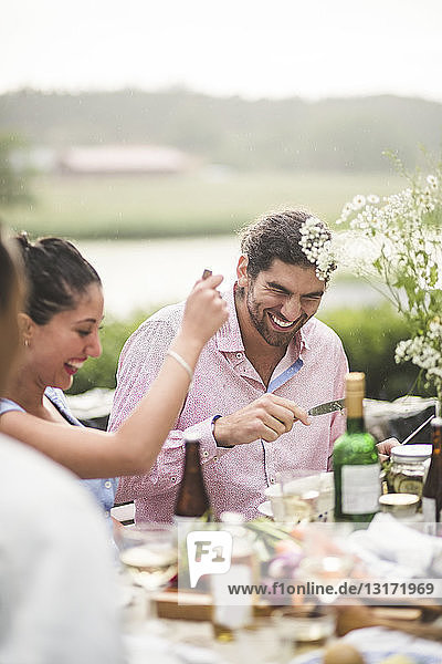 Cheerful male and female friends enjoying dinner party during in backyard