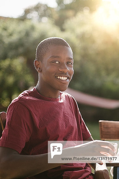 Porträt eines Jungen  der während einer Gartenparty beim Trinken lächelt