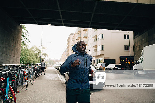 Männlicher Athlet joggt auf dem Bürgersteig in der Stadt