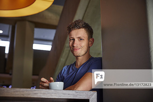 Porträt eines lächelnden jungen Mannes in einem Cafe