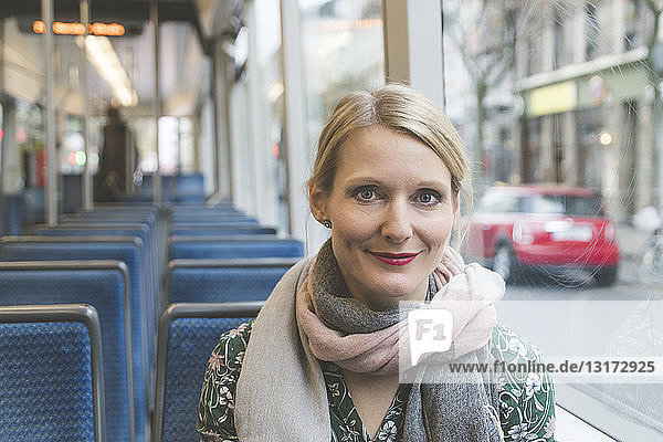 Porträt einer lächelnden Frau  die in der Straßenbahn sitzt