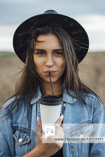 Porträt einer jungen Frau  die ein Getränk trinkt